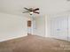 A large bedroom with carpet, a ceiling fan, two doors, and an entry into another room at 2515 Walnut Forest Dr, Charlotte, NC 28216