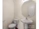 Powder room with pedestal sink, toilet, and octagonal mirror at 2515 Walnut Forest Dr, Charlotte, NC 28216