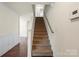 Carpeted staircase with a wooden handrail leading to the upper level, complemented by hardwood floors at 2515 Walnut Forest Dr, Charlotte, NC 28216