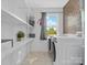 Functional laundry room equipped with washer, dryer, storage shelves, and a bright window at 2633 N Sharon Amity Rd, Charlotte, NC 28205