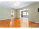 Open living room with hardwood floors leading to a bright sunroom, a ceiling fan, and wall-mounted TV bracket at 2715 Kennetuck Ct, Charlotte, NC 28273
