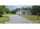 Inviting single-story home with a gravel driveway, lush green lawn, and mature trees surrounding the property at 2820 Bellhaven Cir, Charlotte, NC 28214