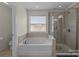 Bright bathroom features a large soaking tub and separate tiled shower with glass door at 2835 Berkhamstead Cir, Concord, NC 28027