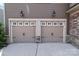 Attached two-car garage doors with carriage accents, decorative lamps, and a concrete driveway at 2835 Berkhamstead Cir, Concord, NC 28027