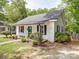 Exterior shot of a quaint house with a porch, lush greenery, and stone walkway, creating a welcoming curb appeal at 318 Chestnut Ave, Kannapolis, NC 28081