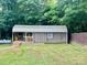 Exterior of a storage shed with covered porch and adjacent grassy area surrounded by trees at 35 Caldwell Dr, Taylorsville, NC 28681