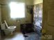 Damaged bathroom with a window, toilet, and deteriorated wall and floor at 421 W Cemetery St, Salisbury, NC 28144