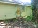 Exterior view of home with yellow siding, door, window, and overgrown landscape at 421 W Cemetery St, Salisbury, NC 28144