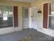 Front porch with peeling paint, showing a front door and adjacent window with maroon shutters at 421 W Cemetery St, Salisbury, NC 28144