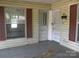 Front porch with peeling paint, showing a front door and adjacent window with maroon shutters at 421 W Cemetery St, Salisbury, NC 28144