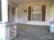 Porch view showing peeling paint, maroon shutters, the front door, and overgrown yard at 421 W Cemetery St, Salisbury, NC 28144
