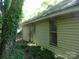 Side exterior view with yellow siding, lush greenery, and a partial view of the yard at 421 W Cemetery St, Salisbury, NC 28144
