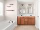 Bathroom showcasing a double vanity with a wood cabinet, a soaking tub, and decorative shelves at 4352 Haddington Dr, Fort Mill, SC 29707