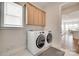 Laundry room with washer, dryer, wood cabinets, and window with view of the dining area at 4689 Kingswood Dr, Indian Land, SC 29707