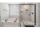 Bright bathroom featuring a luxurious soaking tub and a glass-enclosed shower with marble tile at 5121 Ennisworth Ln, Charlotte, NC 28214