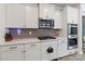 Stylish kitchen featuring white cabinets, stainless steel appliances, and gray backsplash at 5121 Ennisworth Ln, Charlotte, NC 28214