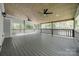 A covered deck with tongue and groove ceilings, fans, and wooden railing overlooks a wooded back yard at 7435 Hammond Dr, Charlotte, NC 28215
