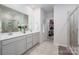 A large mirror, dual sinks, quartz counters, tile flooring, and a walk-in shower highlight the en-suite bathroom at 7530 Porrera St, Charlotte, NC 28214