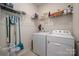 Functional laundry room with washer, dryer, shelving, and cleaning supplies at 7530 Porrera St, Charlotte, NC 28214