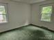 Bedroom features large windows overlooking green space and green carpet at 7608 Surreywood Pl, Charlotte, NC 28270