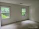 Bright bedroom boasts natural light through two windows, showcasing the peaceful ambiance and carpeted floors at 7608 Surreywood Pl, Charlotte, NC 28270