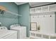 Well-organized laundry room with washer, dryer, shelving, and a mudroom bench with hooks at 8406 Flint Hill Dr, Charlotte, NC 28273