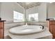 Bright bathroom showcasing a large soaking tub with a view from multiple windows at 8493 Twickenham Ter, Harrisburg, NC 28075