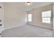 Bright bedroom with neutral carpet and two windows providing ample natural light at 8493 Twickenham Ter, Harrisburg, NC 28075