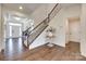 Elegant foyer showcasing hardwood floors, staircase with iron railing, and natural light at 8493 Twickenham Ter, Harrisburg, NC 28075