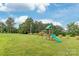Spacious backyard with green lawn and wooden playset featuring a slide and swing for outdoor fun at 8717 Swift Rd, Oakboro, NC 28129