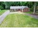 Aerial view of a charming brick home with a well-manicured lawn and a long, paved driveway at 8938 Glencroft Rd, Mint Hill, NC 28227
