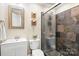 Bathroom with white vanity, toilet, decorative wall sconces, and a shower featuring unique stone tile at 8938 Glencroft Rd, Mint Hill, NC 28227