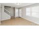 A neutral living room featuring tile flooring, stairs to the second floor, and access to outdoor and other rooms at 9464 Lexington Cir # B, Charlotte, NC 28213