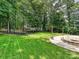 Well-maintained backyard with lush green grass, mature trees, landscaping, and a cozy fire pit area at 9507 Reid Hall Ln, Matthews, NC 28105