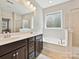 Bathroom with double vanity, a large mirror, and a soaking tub at 9507 Reid Hall Ln, Matthews, NC 28105