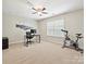 Spacious bedroom with neutral tones, a ceiling fan, large window, and home office and exercise equipment at 9507 Reid Hall Ln, Matthews, NC 28105