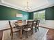 Elegant dining room features rich green walls, wainscoting, a modern chandelier, and a large window at 9507 Reid Hall Ln, Matthews, NC 28105