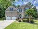 Beautiful two-story home boasts a two-car garage, stone accents, manicured lawn, and mature landscaping at 9507 Reid Hall Ln, Matthews, NC 28105