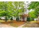 Charming two-story home with a covered porch and balcony, surrounded by mature trees and landscaping at 10407 Alvarado Way, Charlotte, NC 28277