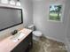 Well-lit bathroom featuring vanity with sink and a large mirror, toilet, and a window for natural light at 10518 Fairway Ridge Rd, Charlotte, NC 28277
