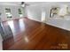Open living room with gleaming hardwood floors, large windows, and a view into the kitchen at 10518 Fairway Ridge Rd, Charlotte, NC 28277