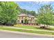 An exterior view showcasing a well-manicured lawn, stone accents, and mature trees at 11052 Preservation Park Dr, Charlotte, NC 28214