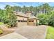A large three car garage and driveway are accompanied by verdant trees and landscaping at 11052 Preservation Park Dr, Charlotte, NC 28214