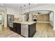 A kitchen island features granite countertops, stainless appliances, a sink, and dark cabinets at 11052 Preservation Park Dr, Charlotte, NC 28214