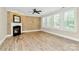 A living room with a fireplace has wood floors, grasscloth wallpaper, natural light, and a ceiling fan at 11052 Preservation Park Dr, Charlotte, NC 28214