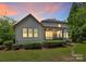 The exterior view of the home at twilight, featuring a screened porch, patio, and landscaped backyard at 11052 Preservation Park Dr, Charlotte, NC 28214