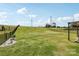 Large grassy backyard with partial fence and outdoor seating area overlooking green space beyond at 15023 Longmoore Dr, Charlotte, NC 28278