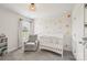 Brightly lit baby room featuring a white crib, accent wall, and a comfortable rocker at 15023 Longmoore Dr, Charlotte, NC 28278