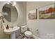 Cozy powder room boasts pedestal sink, toilet, and decorative landscape art at 18145 Sulton Ter, Huntersville, NC 28078