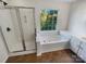 Bathroom with a glass-enclosed shower, a soaking tub by the window, and vanity, providing a luxurious and relaxing experience at 18414 Victoria Bay Dr, Cornelius, NC 28031